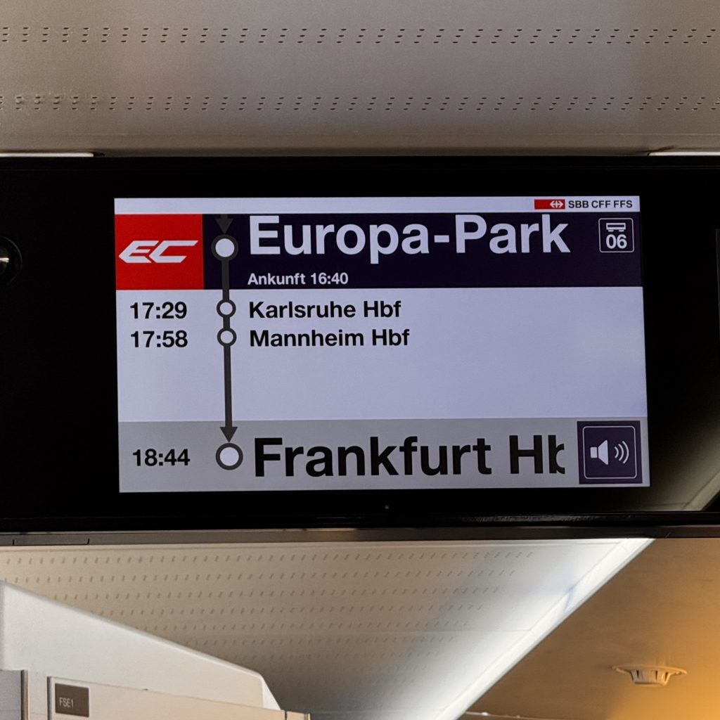 Ein digitales Anzeigetableau in einem Zug zeigt die Fahrt von Europa-Park mit Ankunft um 16:40 Uhr, einschließlich der Haltestellen Karlsruhe Hbf um 17:29 Uhr, Mannheim Hbf um 17:58 Uhr und Frankfurt Hbf um 18:44 Uhr.